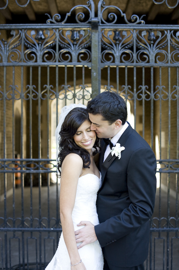 Groom kisses his bride in front of a beautiful iron gate- wedding photo by top Canadian wedding photographer Rebecca Wood
